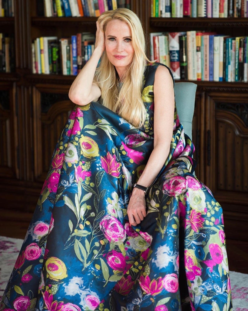Woman in a floor-length black gown with vibrant floral print posing on the red carpet at The Author Incubator event, holding the book Meant for More by Mia Hewett.