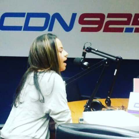 Melina Nmili speaking into a microphone during Republica Dominicana Fashion Week 2017 media tour at CDN 92.5 radio station.