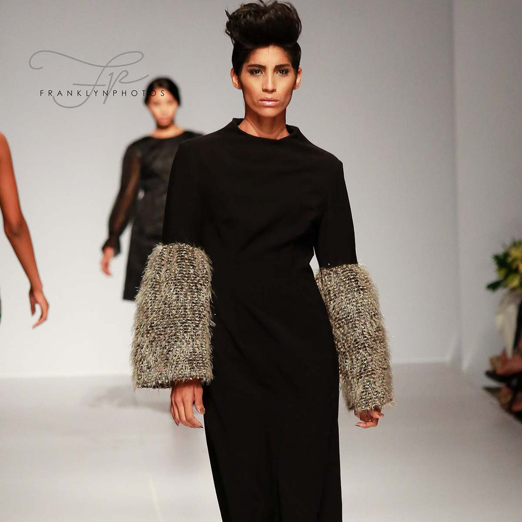 Model walking runway in black dress with textured sleeves at Republica Dominicana Fashion Week 2017.