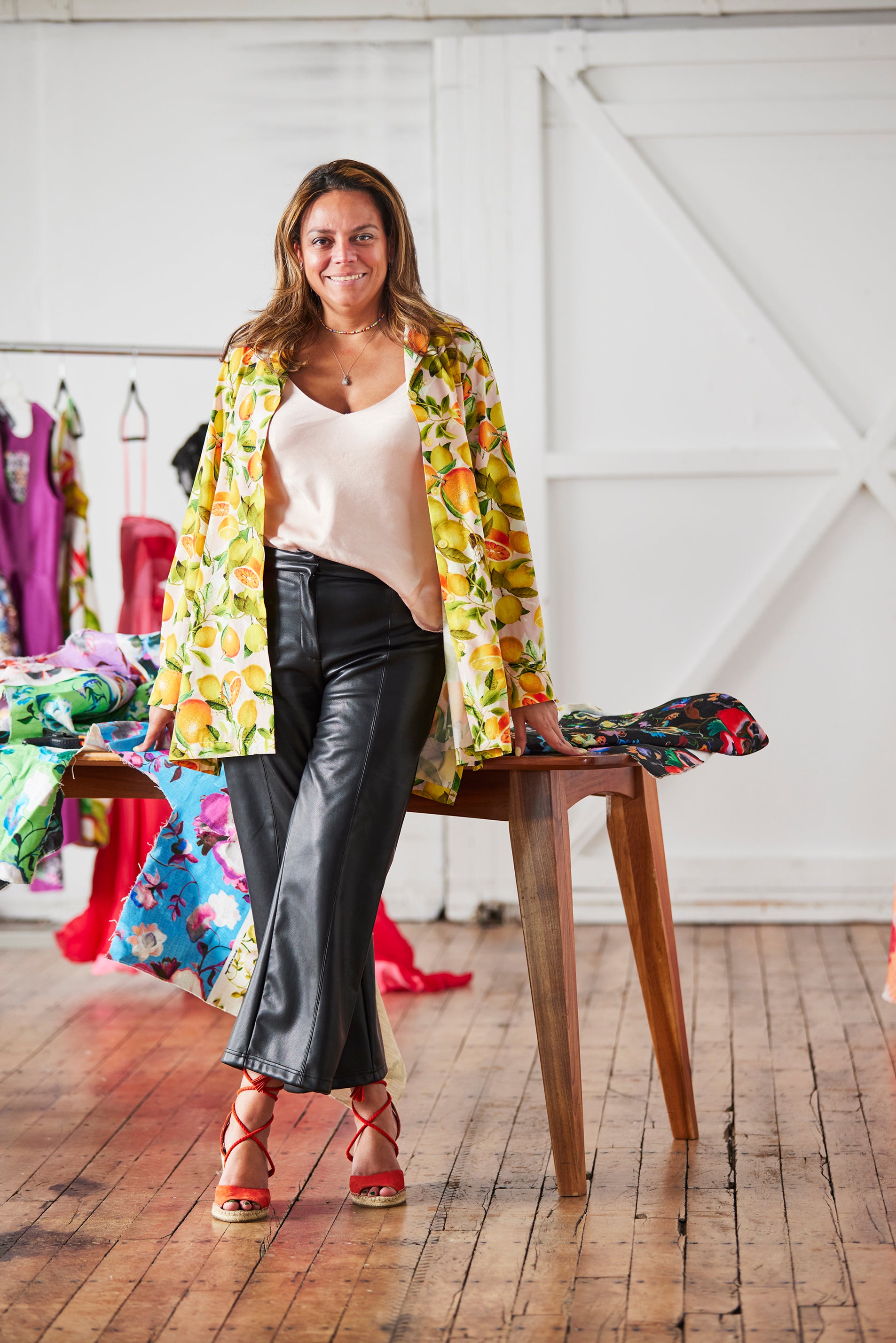 Melina, woman standing in front of her luxury dress pieces