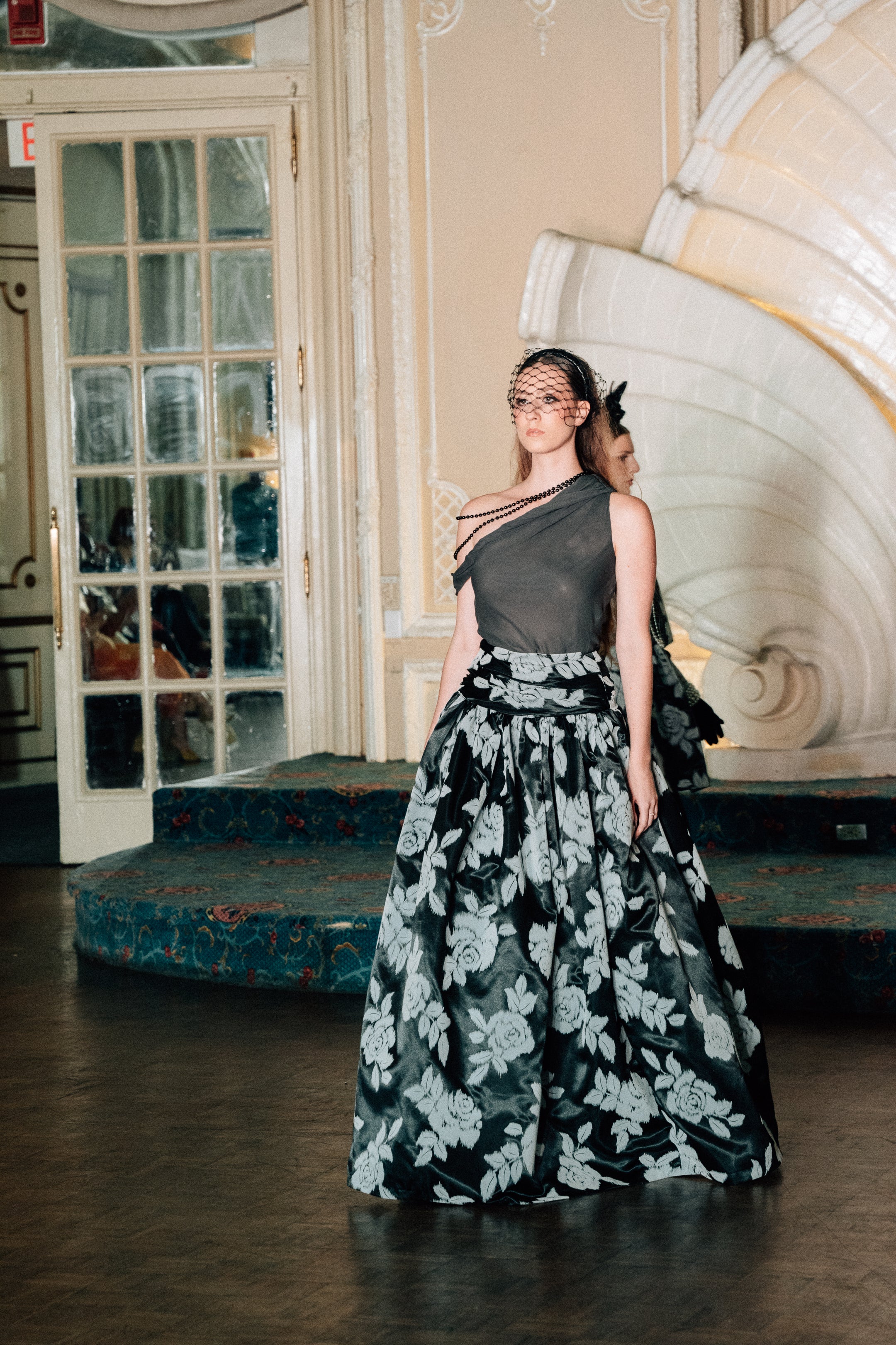 Model wearing the Lalla Bee Jennifer custom design gown featuring a sleek one-shoulder bodice and full black floral skirt—ideal for galas and formal events.