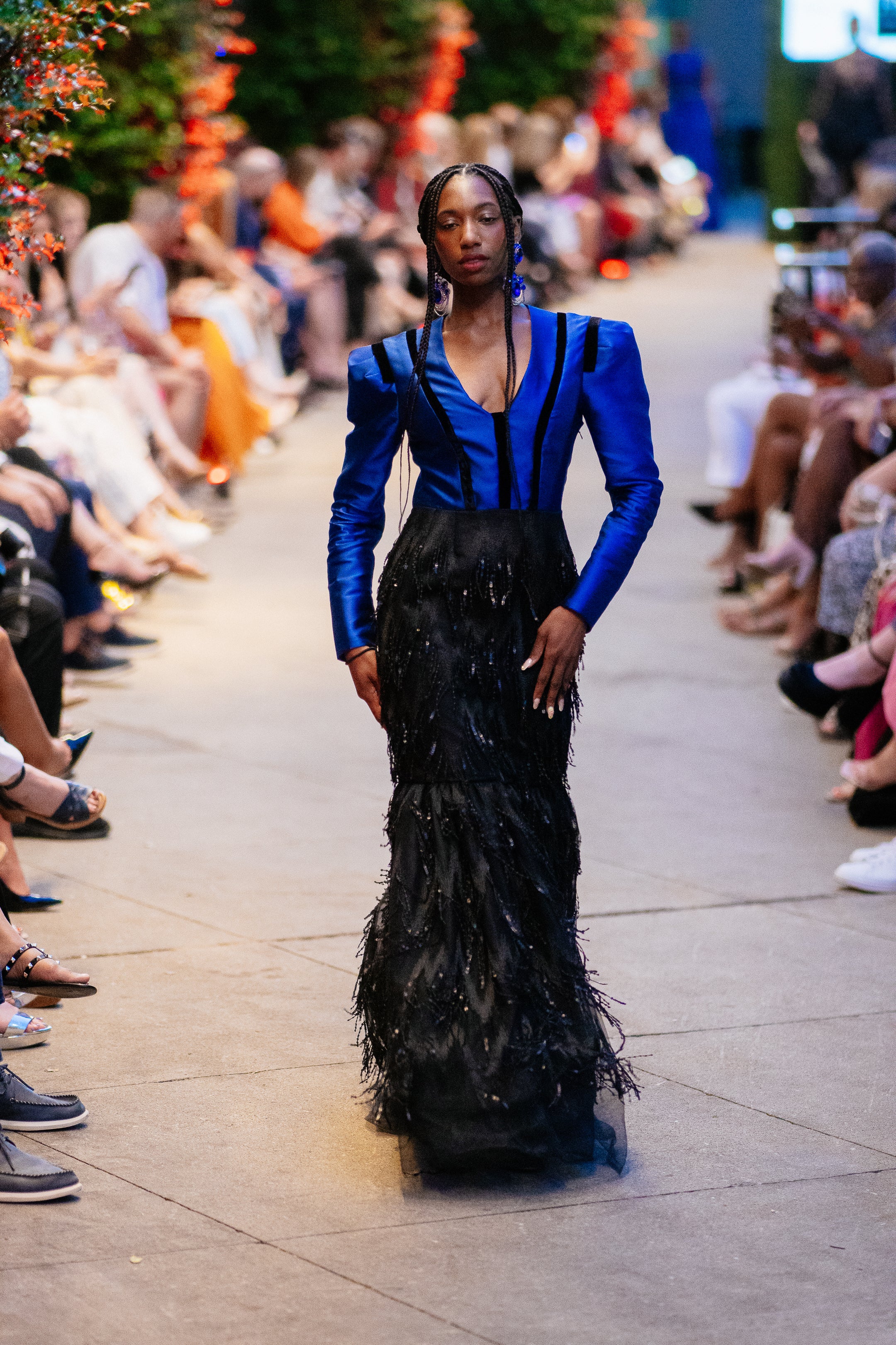Model wearing the Lalla Bee Matador custom design gown with a structured royal blue top, deep neckline, and black feathered skirt—ideal for galas and special events.

